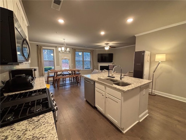 kitchen featuring visible vents, dishwasher, a fireplace, white cabinetry, and a sink