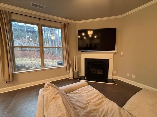 living area with visible vents, crown molding, baseboards, and wood finished floors