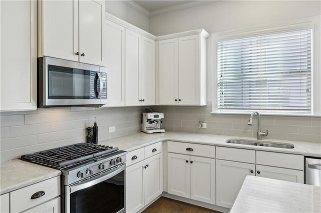 kitchen featuring appliances with stainless steel finishes, white cabinetry, tasteful backsplash, and sink