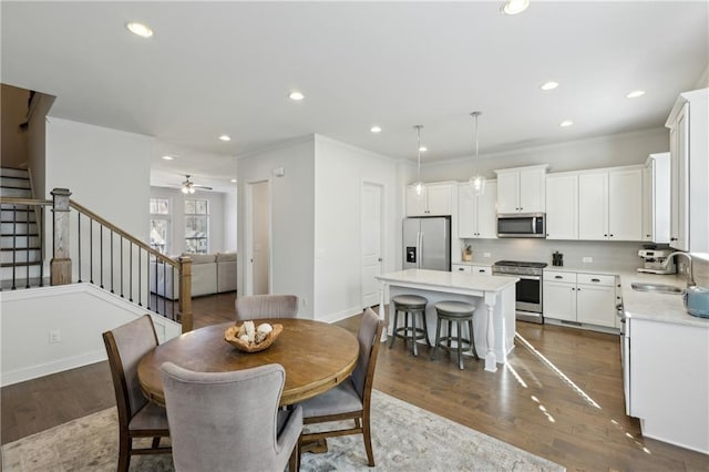 dining space with sink, ceiling fan, crown molding, and dark hardwood / wood-style floors