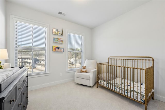 bedroom featuring a nursery area and light colored carpet