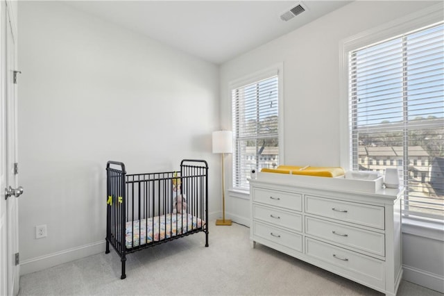 bedroom featuring a nursery area and light carpet