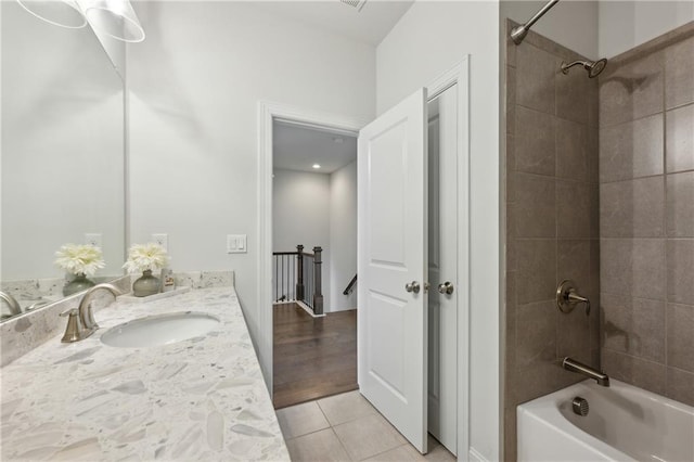 bathroom featuring tile patterned flooring, tiled shower / bath, and vanity