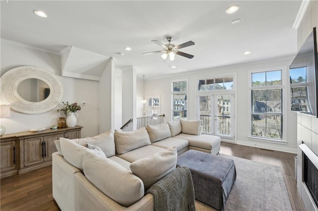 living room featuring ceiling fan, dark hardwood / wood-style flooring, a tile fireplace, and crown molding