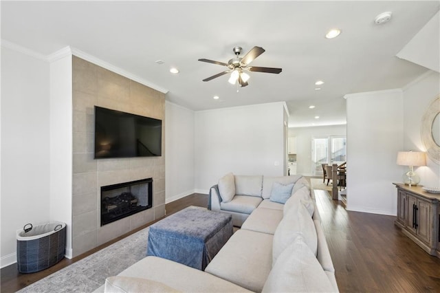 living room with ceiling fan, dark wood-type flooring, ornamental molding, and a fireplace