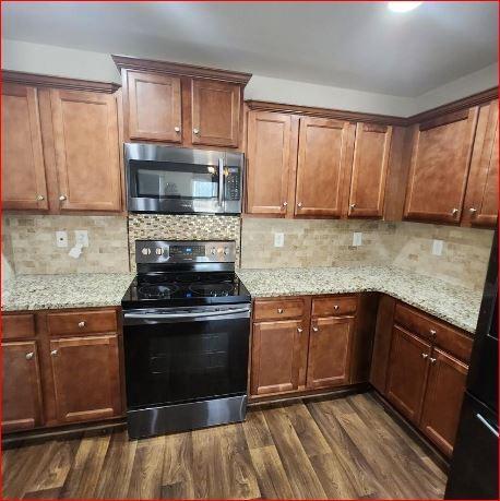 kitchen featuring electric stove, dark hardwood / wood-style floors, light stone countertops, and tasteful backsplash