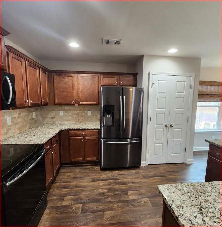 kitchen featuring light stone counters, dark hardwood / wood-style floors, black electric range, and stainless steel fridge with ice dispenser