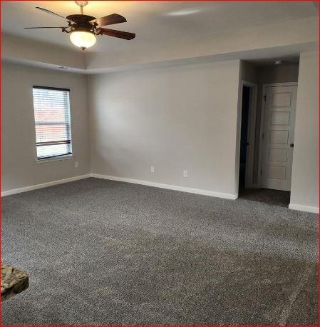 carpeted spare room with a tray ceiling and ceiling fan