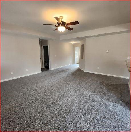 unfurnished room with dark colored carpet and ceiling fan