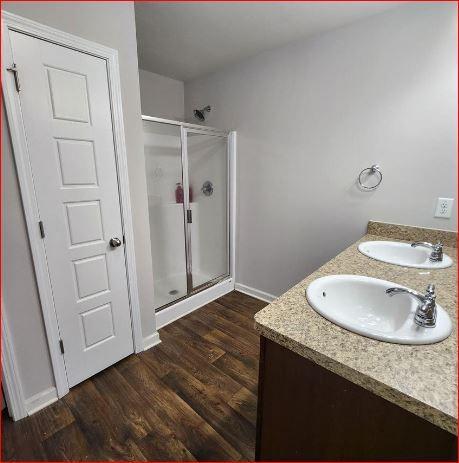 bathroom with vanity, a shower with shower door, and hardwood / wood-style floors