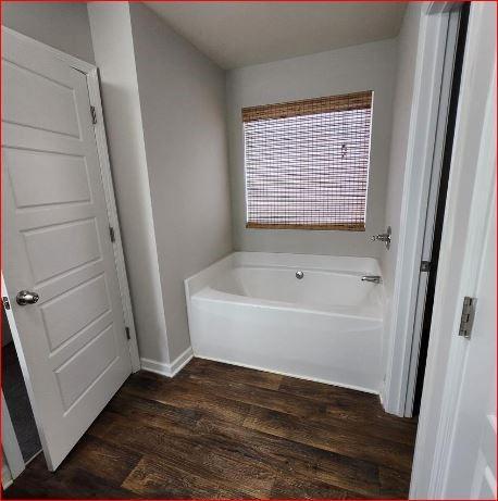 bathroom with hardwood / wood-style flooring and a tub to relax in