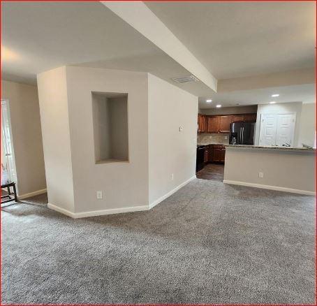 unfurnished living room with dark carpet