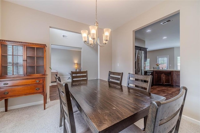 dining room with a chandelier and light colored carpet