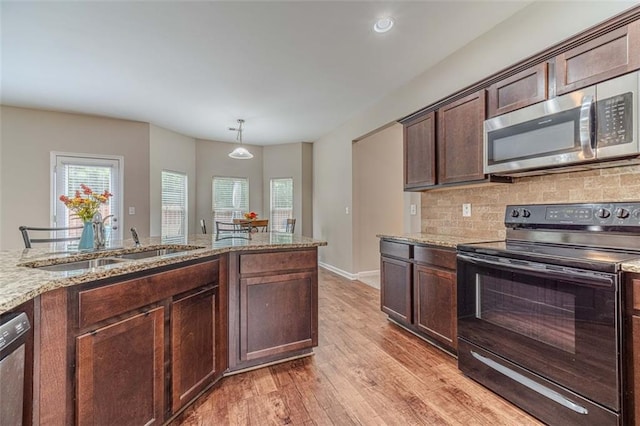 kitchen featuring stainless steel appliances, light wood-style floors, plenty of natural light, and light stone countertops