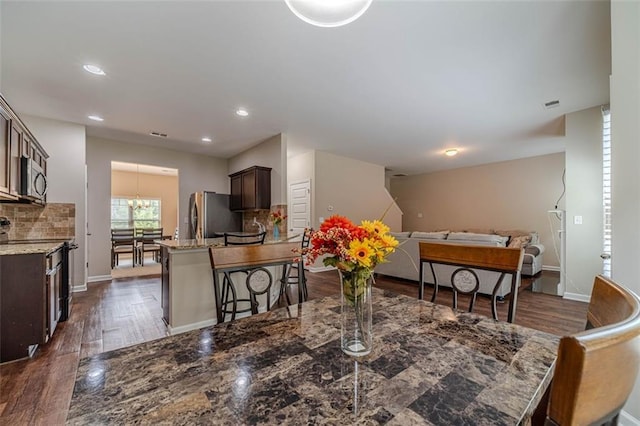 dining space with dark wood finished floors, a chandelier, and recessed lighting