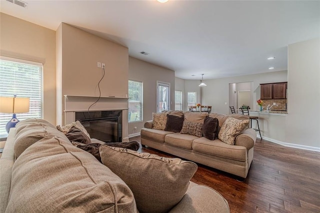 living area with dark wood-style flooring, recessed lighting, and a glass covered fireplace