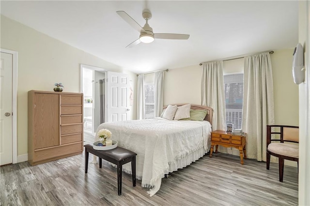 bedroom featuring ceiling fan, vaulted ceiling, multiple windows, and light hardwood / wood-style flooring