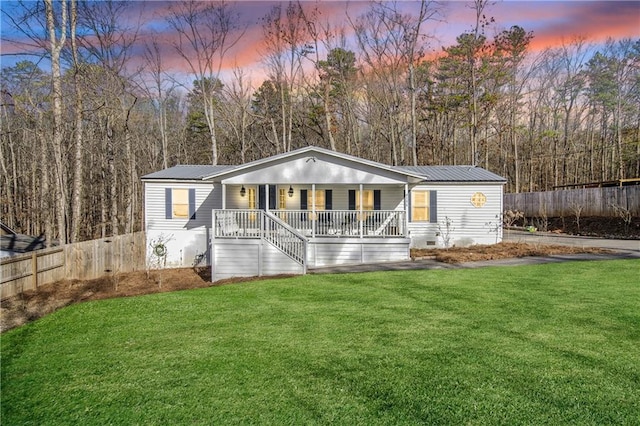 back house at dusk with a porch and a lawn