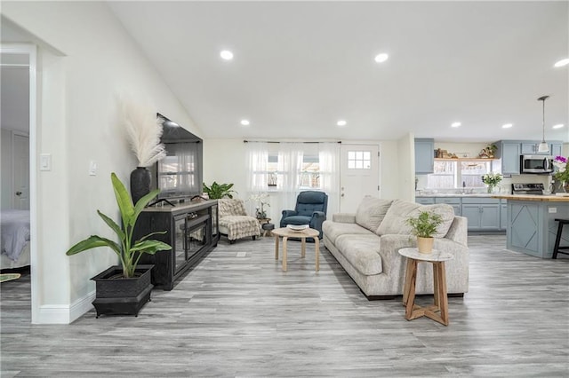 living room featuring a wealth of natural light, lofted ceiling, and light hardwood / wood-style flooring