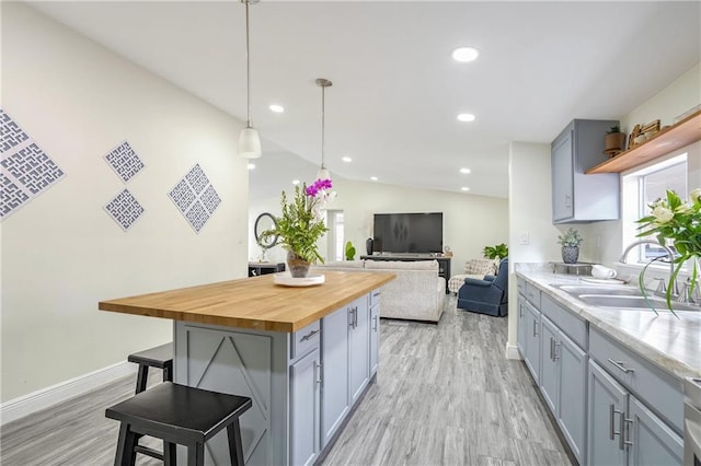 kitchen with wooden counters, a breakfast bar area, decorative light fixtures, a kitchen island, and sink