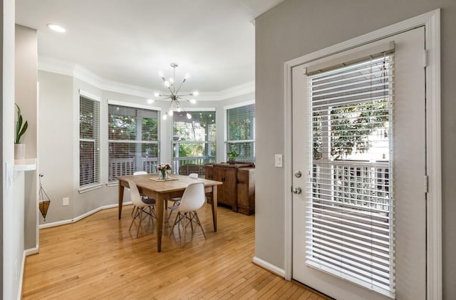 dining area featuring a chandelier, light wood-type flooring, crown molding, and baseboards