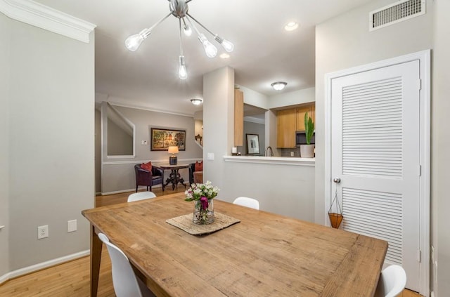 dining space featuring ornamental molding, light wood-type flooring, visible vents, and baseboards