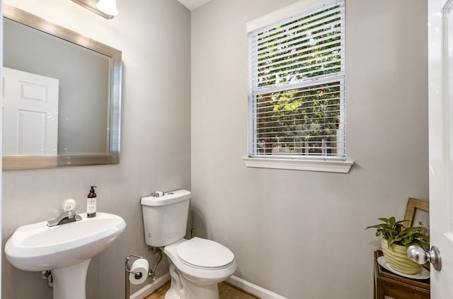 half bath featuring baseboards, a sink, and toilet