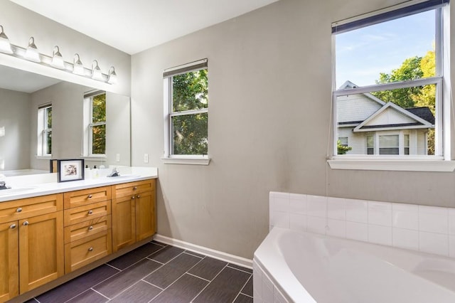 bathroom featuring double vanity, baseboards, a garden tub, wood finish floors, and a sink