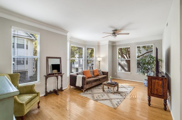 sitting room with light wood-style floors, crown molding, baseboards, and ceiling fan