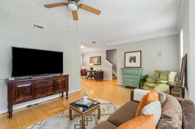 living area featuring light wood-type flooring, visible vents, and crown molding