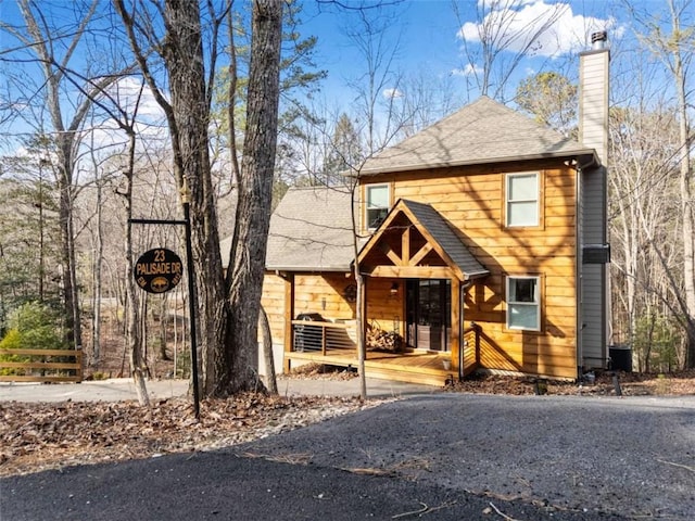 view of front of property with covered porch, roof with shingles, and a chimney