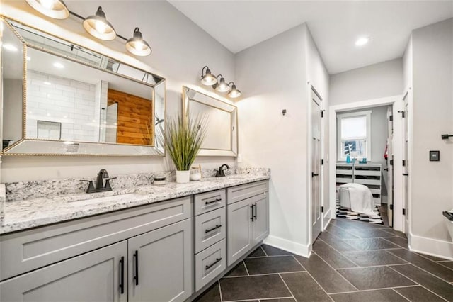 bathroom with double vanity, tile patterned flooring, baseboards, and a sink