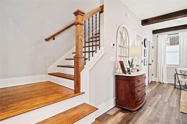 stairs with beamed ceiling, wood finished floors, and baseboards