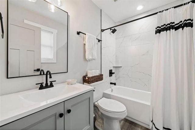 bathroom with toilet, shower / bathtub combination with curtain, wood finished floors, and vanity