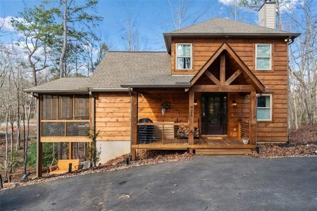 view of front of property featuring a chimney, a porch, and roof with shingles