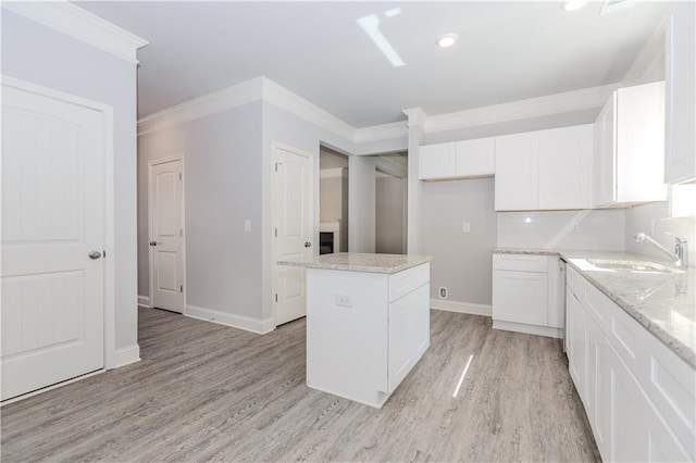 kitchen featuring ornamental molding, a center island, a sink, and light wood finished floors