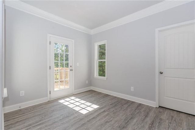 unfurnished room featuring baseboards, wood finished floors, and crown molding