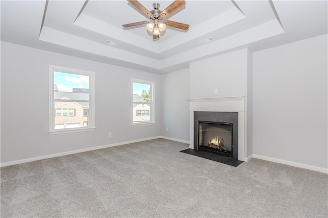unfurnished living room with a fireplace with flush hearth, a raised ceiling, a ceiling fan, and baseboards