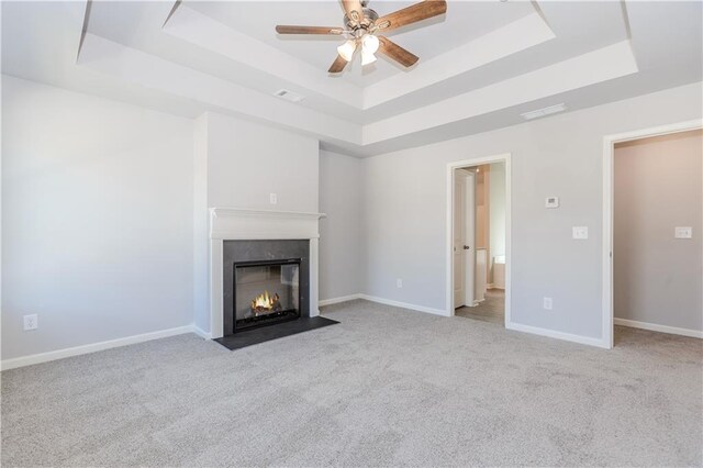 unfurnished living room with carpet floors, a raised ceiling, visible vents, and a premium fireplace