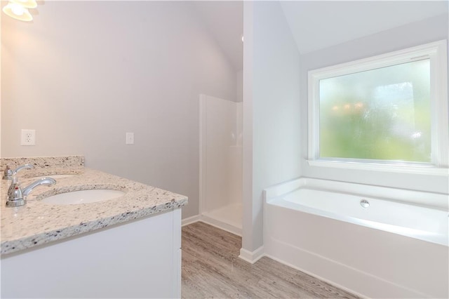 full bath with a garden tub, vaulted ceiling, wood finished floors, baseboards, and walk in shower