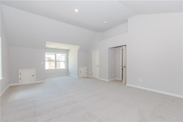 unfurnished room with lofted ceiling, light carpet, and baseboards