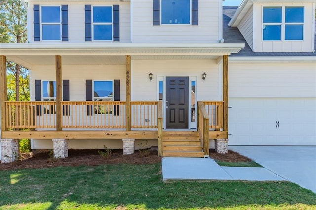 view of exterior entry featuring a porch, driveway, and a garage