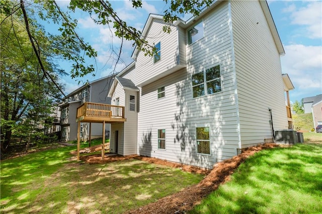 rear view of property with a yard, a deck, and central AC unit