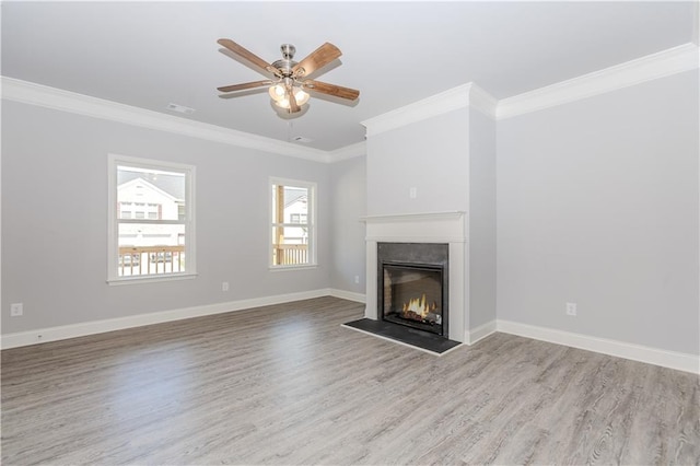 unfurnished living room featuring a lit fireplace, ornamental molding, wood finished floors, and baseboards