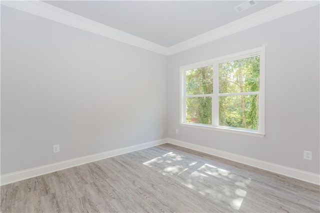 empty room with light wood-type flooring, baseboards, visible vents, and crown molding