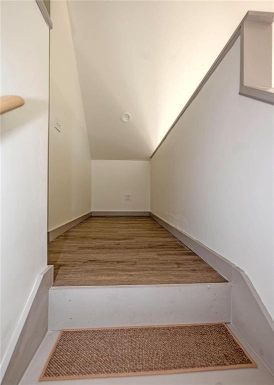 stairs with vaulted ceiling and wood finished floors