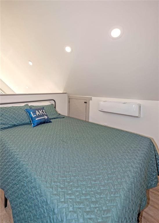 bedroom featuring vaulted ceiling, wood finished floors, recessed lighting, and a wall mounted AC