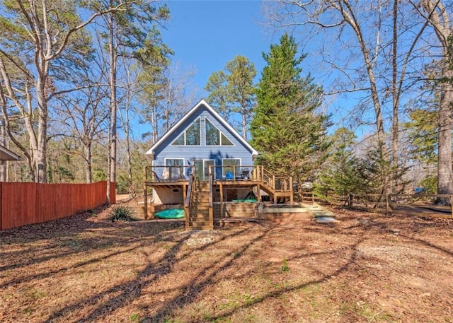 rear view of property featuring stairway, a deck, and fence