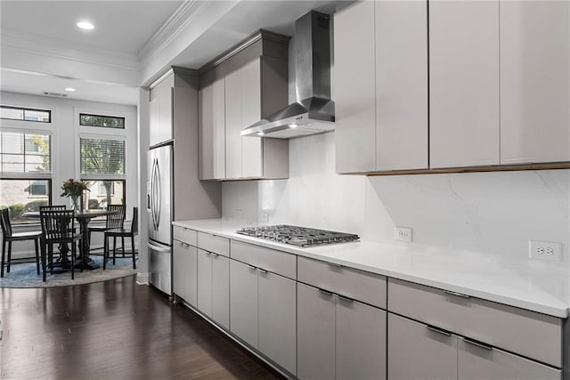 kitchen featuring wall chimney range hood, gray cabinetry, stainless steel appliances, decorative backsplash, and dark hardwood / wood-style flooring