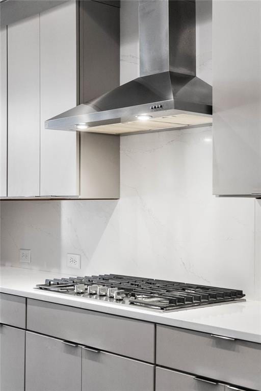 kitchen with stainless steel gas stovetop, backsplash, and wall chimney range hood